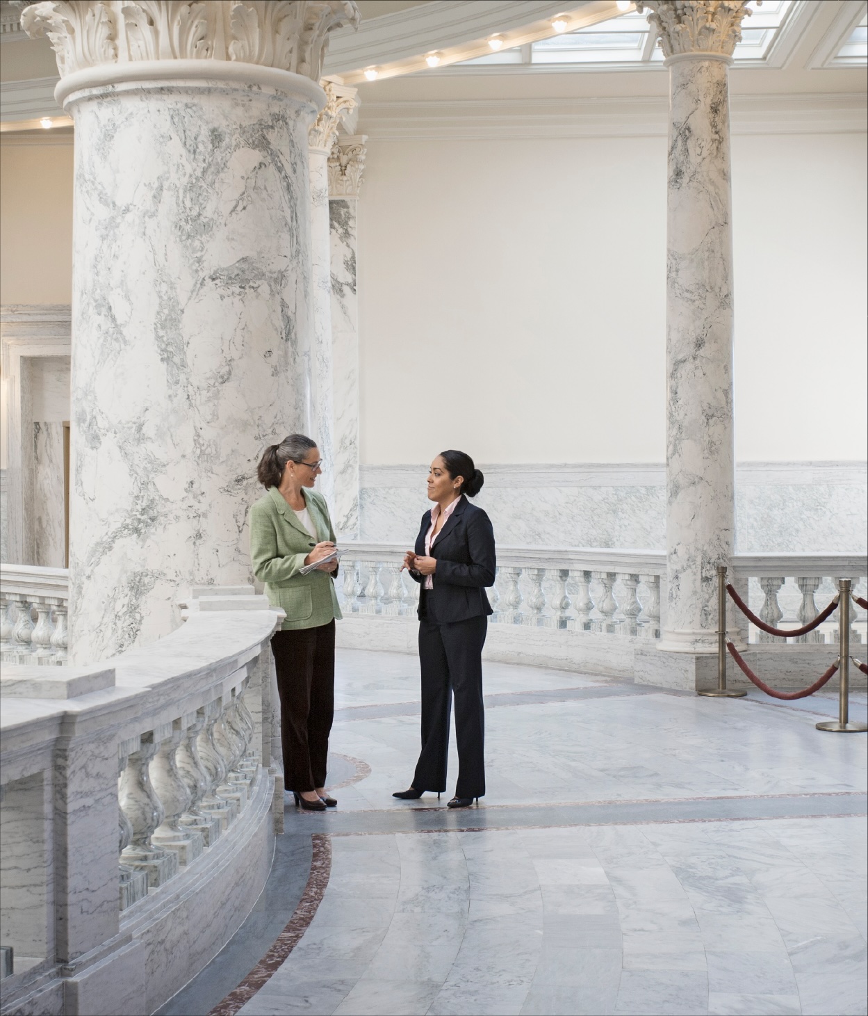 Two women have a conversation in a statehouse.